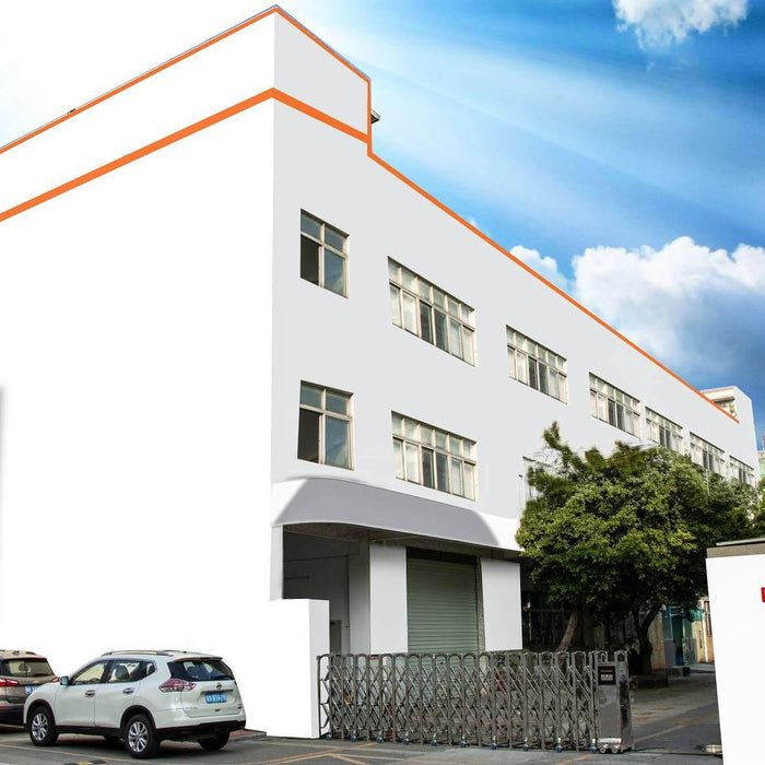 White industrial building with RALCAM signage and parked cars under blue sky with clouds